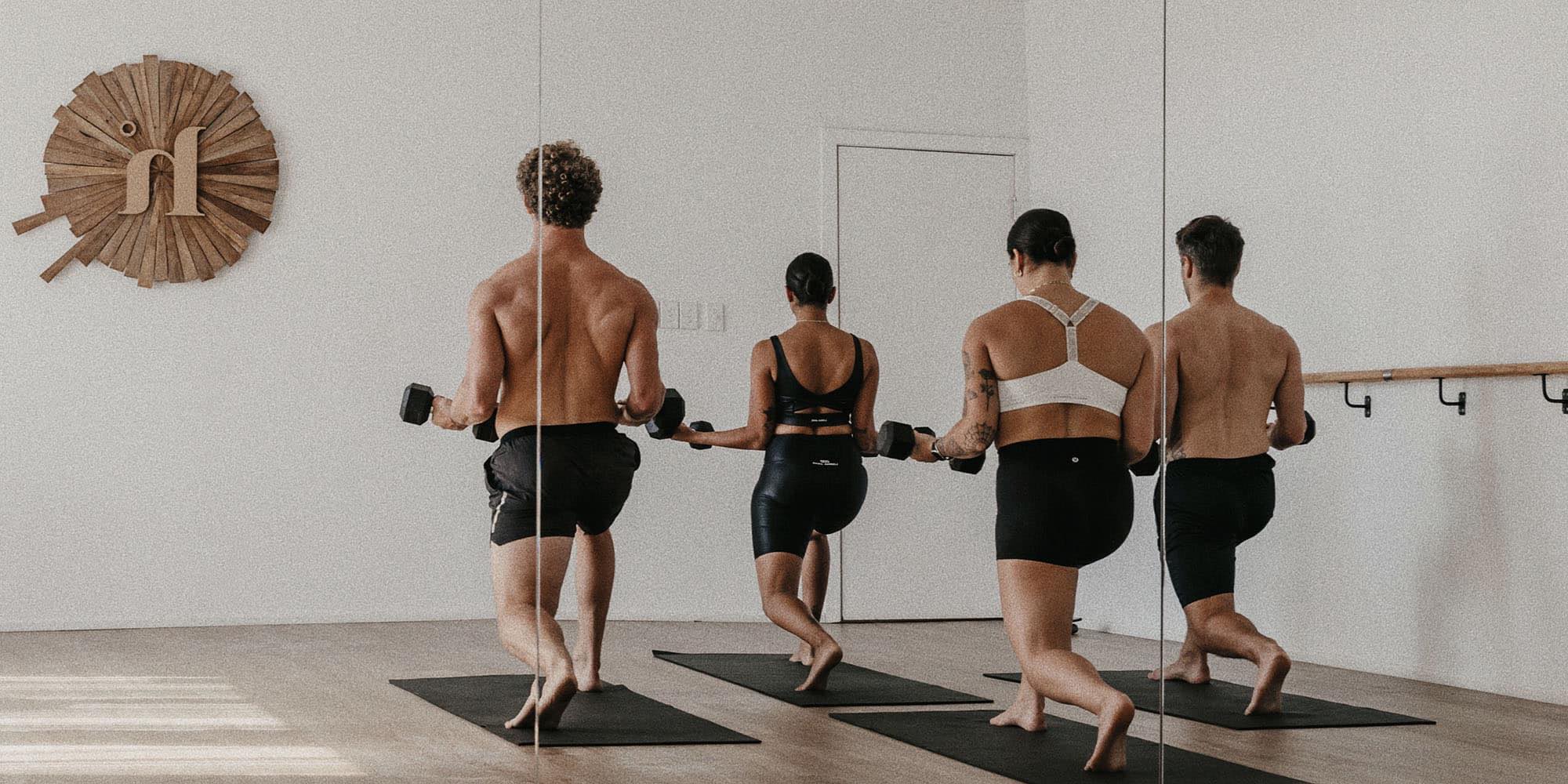 Four Yogis Lifting Weights On a Yoga Mat at Heat Yoga in Byron Bay
